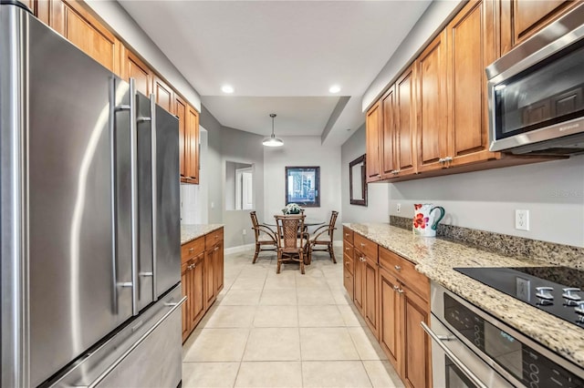 kitchen with decorative light fixtures, light tile patterned flooring, light stone countertops, and appliances with stainless steel finishes