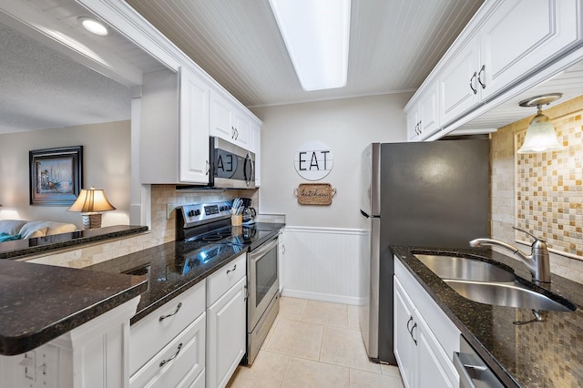 kitchen featuring appliances with stainless steel finishes, white cabinetry, kitchen peninsula, and sink