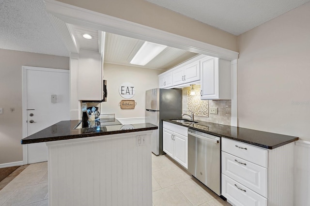 kitchen featuring a textured ceiling, light tile patterned floors, white cabinetry, appliances with stainless steel finishes, and sink