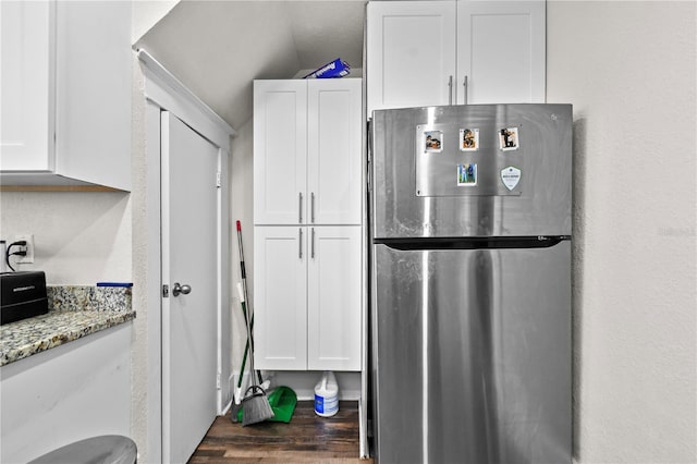 kitchen featuring stainless steel refrigerator, light stone counters, white cabinets, and vaulted ceiling