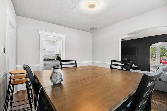 dining room featuring a textured ceiling and dark hardwood / wood-style floors