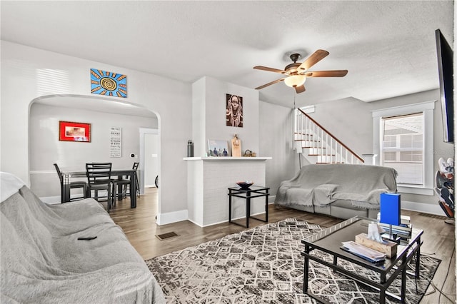 living room featuring ceiling fan, wood-type flooring, and a textured ceiling