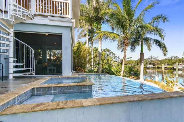 view of pool featuring an in ground hot tub, a water view, and a patio