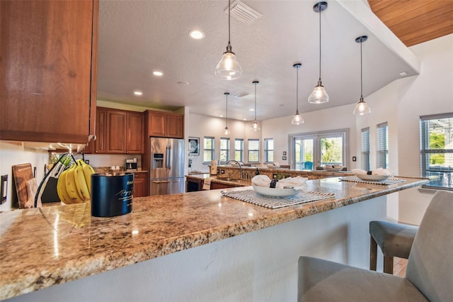 kitchen featuring a breakfast bar area, stainless steel fridge with ice dispenser, plenty of natural light, and pendant lighting