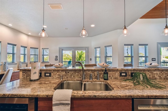 kitchen with backsplash, decorative light fixtures, plenty of natural light, and sink