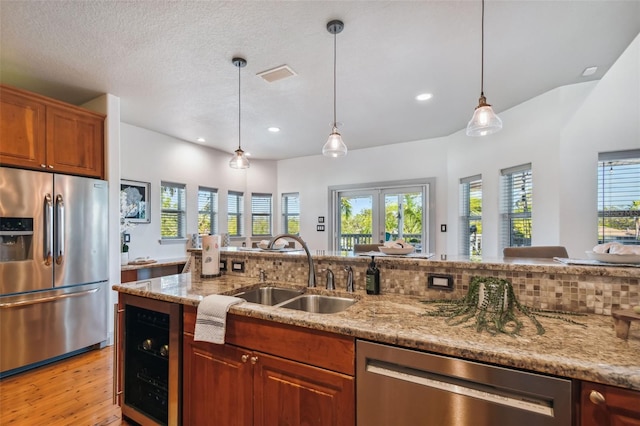 kitchen with wine cooler, sink, pendant lighting, and appliances with stainless steel finishes