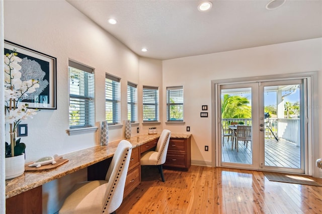 home office featuring french doors, built in desk, a textured ceiling, and light wood-type flooring