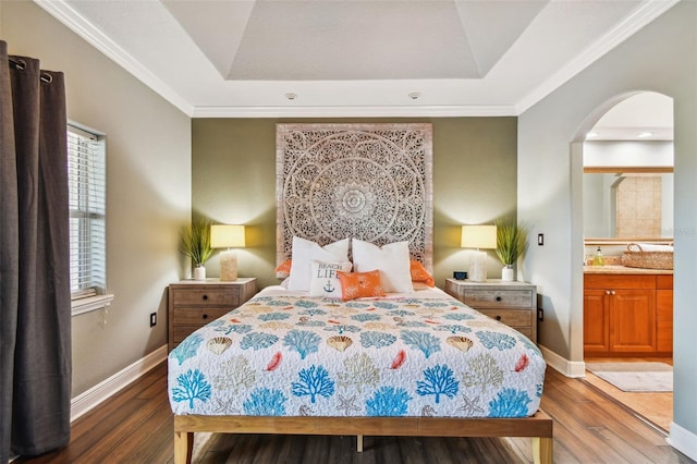 bedroom featuring ensuite bathroom, dark hardwood / wood-style floors, ornamental molding, and a tray ceiling