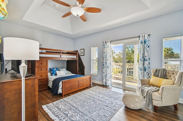 bedroom with a raised ceiling, ceiling fan, dark hardwood / wood-style flooring, and access to exterior