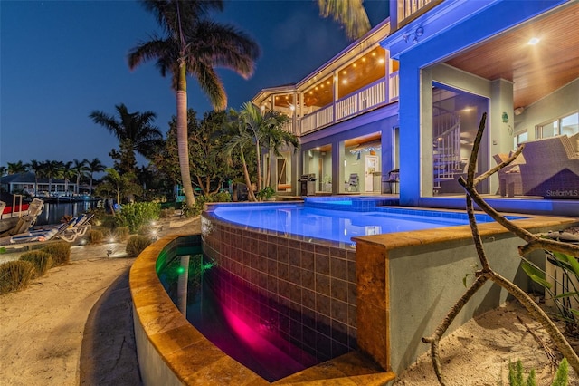 pool at night with an in ground hot tub