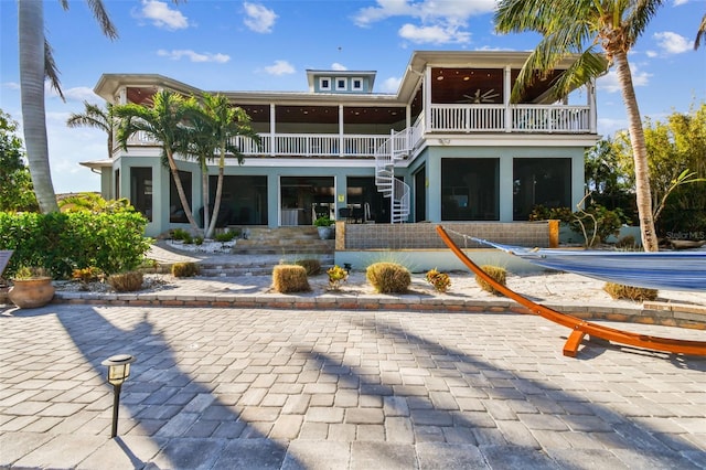 rear view of house featuring a sunroom, ceiling fan, and a balcony