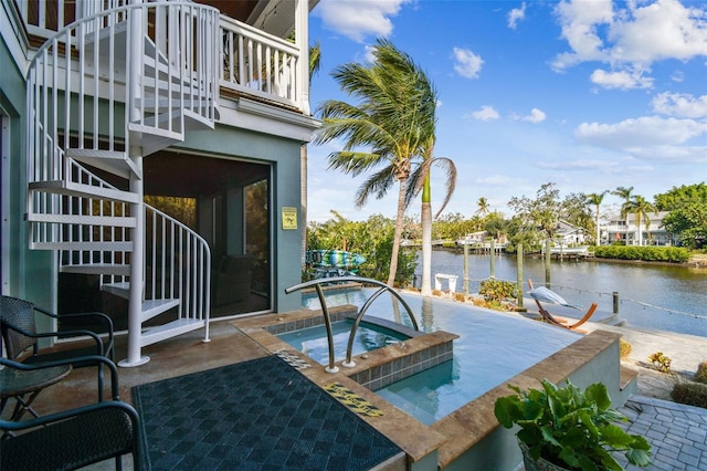 view of pool featuring a water view, an in ground hot tub, and a patio