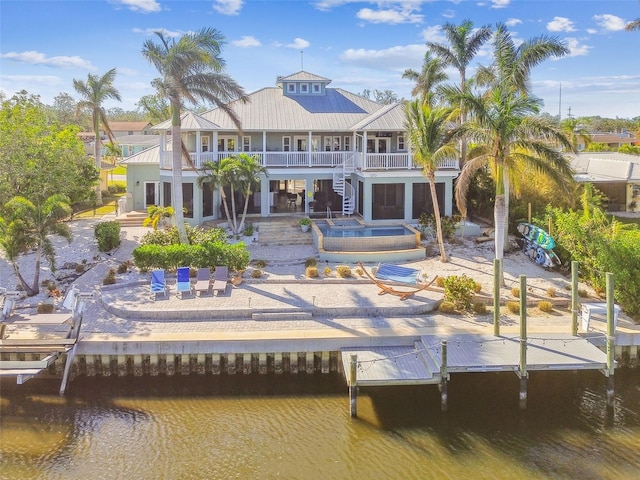 rear view of property with a balcony, a water view, and a patio area