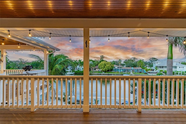 deck at dusk featuring a water view