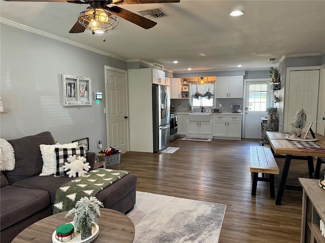 living room featuring ceiling fan, sink, ornamental molding, and dark wood-type flooring