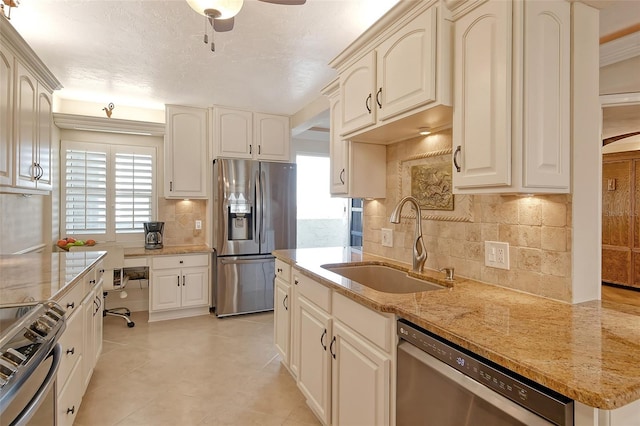 kitchen featuring sink, tasteful backsplash, appliances with stainless steel finishes, ceiling fan, and light stone countertops