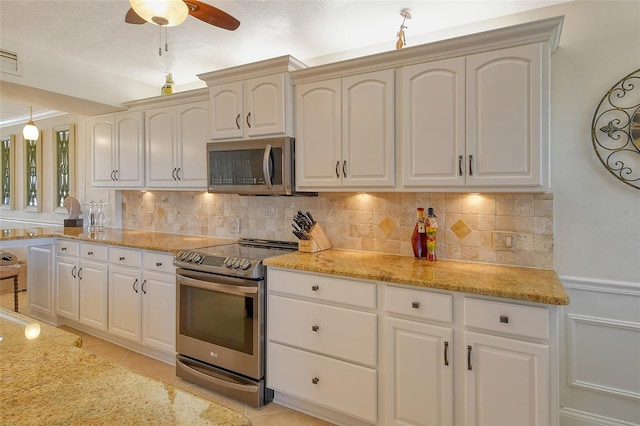 kitchen featuring stainless steel appliances, light tile patterned flooring, white cabinets, and backsplash