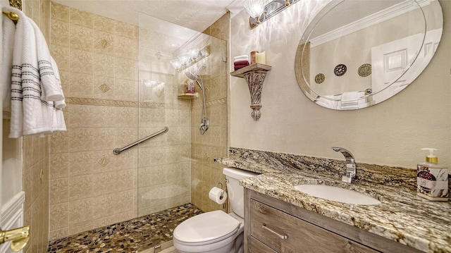 bathroom featuring vanity, tiled shower, ornamental molding, and toilet