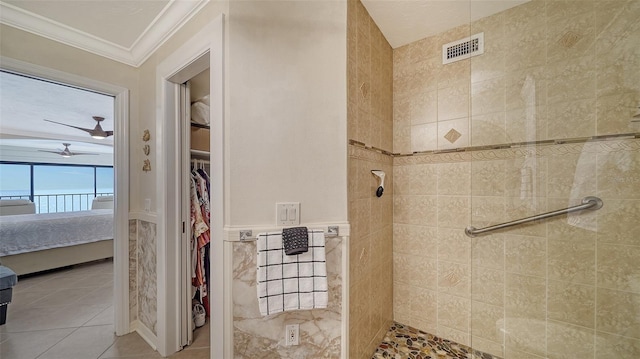 bathroom with tile walls, tile patterned flooring, ornamental molding, tiled shower, and ceiling fan