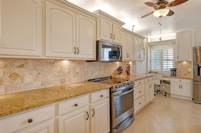 kitchen featuring light tile patterned flooring, light stone counters, ceiling fan, stainless steel appliances, and decorative backsplash