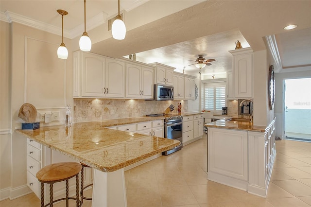 kitchen featuring sink, light stone counters, hanging light fixtures, kitchen peninsula, and stainless steel appliances