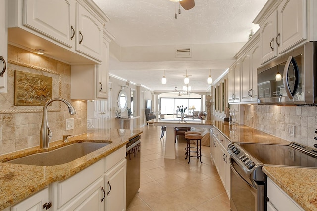 kitchen featuring light stone counters, sink, decorative light fixtures, and stainless steel appliances