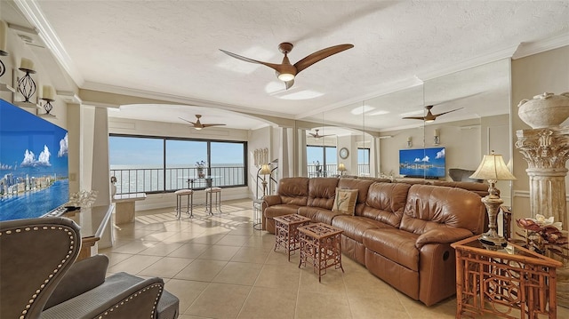 tiled living room featuring a textured ceiling, ornamental molding, ceiling fan, and a water view