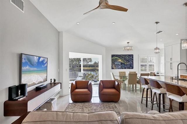 living room with ceiling fan with notable chandelier, lofted ceiling, and sink