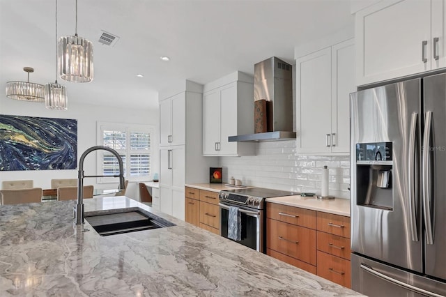 kitchen with sink, wall chimney exhaust hood, light stone countertops, white cabinetry, and stainless steel appliances