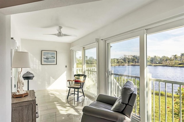 sunroom / solarium featuring ceiling fan and a water view