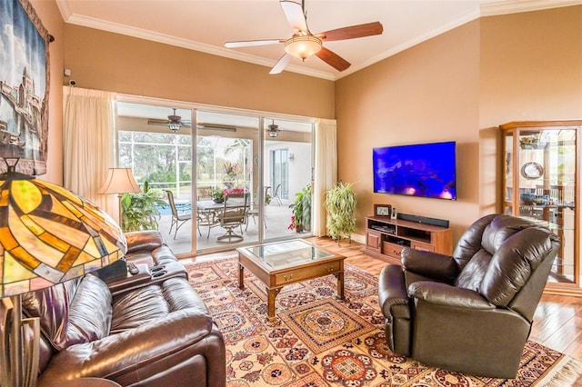 living area with ornamental molding, wood finished floors, a ceiling fan, and baseboards