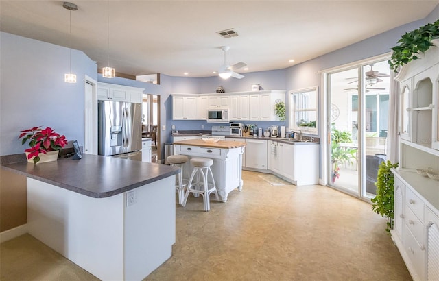 kitchen featuring white appliances, visible vents, a ceiling fan, a peninsula, and a sink