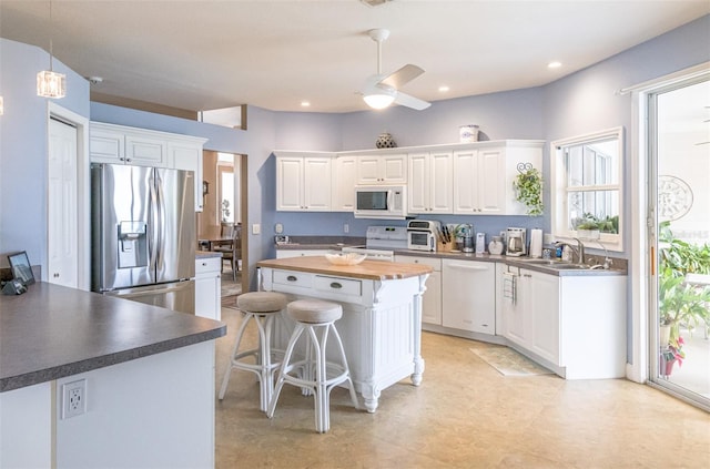 kitchen with a ceiling fan, a center island, white appliances, and white cabinetry