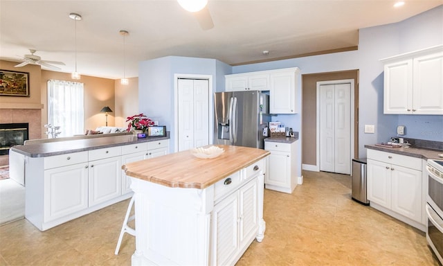 kitchen with stainless steel fridge, ceiling fan, a peninsula, and white cabinetry