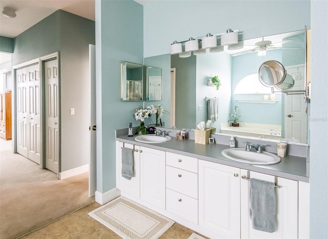 bathroom with a garden tub, ceiling fan, baseboards, and a sink