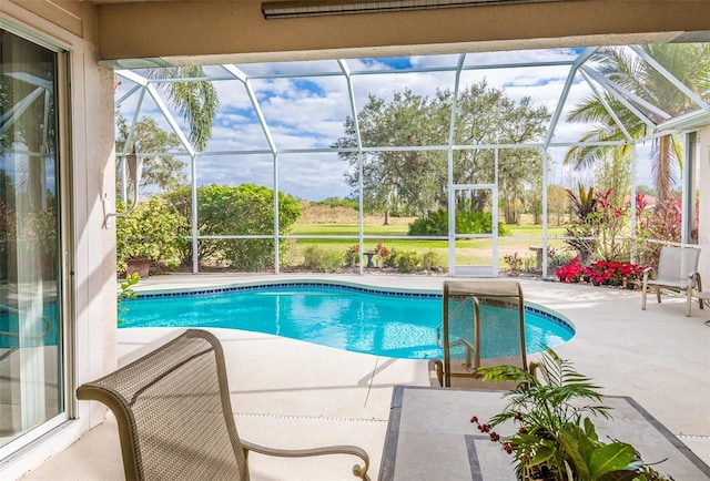 outdoor pool featuring glass enclosure and a patio