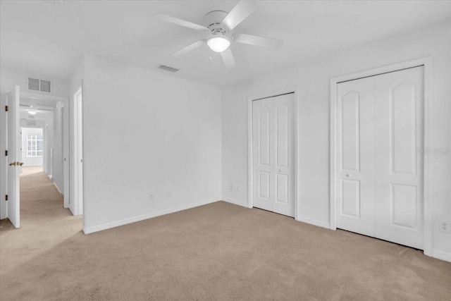 unfurnished bedroom featuring light carpet, two closets, and ceiling fan