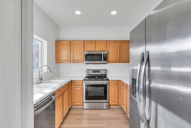 kitchen with stainless steel appliances, sink, and light hardwood / wood-style floors