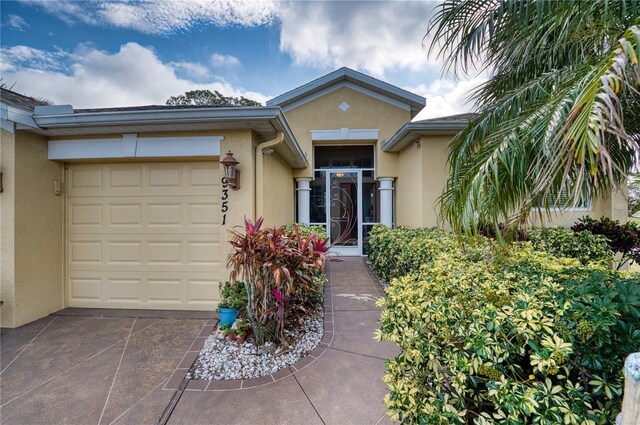 9351 Raes Creek Pl, Palmetto, FL 34221 - view of exterior entry featuring stucco siding, concrete driveway, and a garage