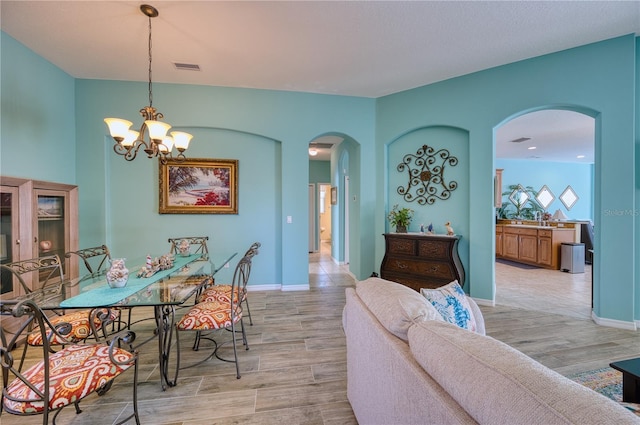 9351 Raes Creek Pl, Palmetto, FL 34221 - dining space with arched walkways, light wood-style floors, and a chandelier