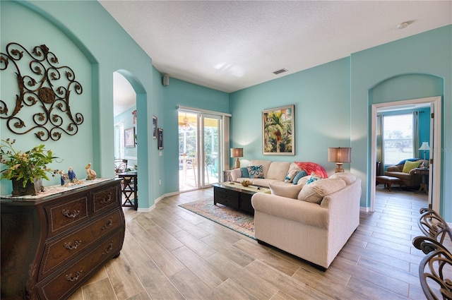 living room with a textured ceiling, light hardwood / wood-style floors, and a healthy amount of sunlight