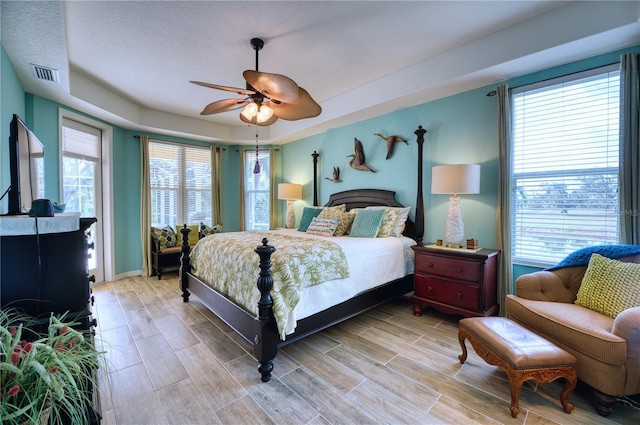 bedroom with a textured ceiling, light hardwood / wood-style flooring, and ceiling fan