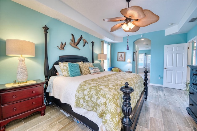 bedroom with ceiling fan, light wood-type flooring, and ensuite bath