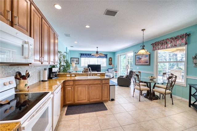 kitchen featuring sink, kitchen peninsula, decorative light fixtures, white appliances, and decorative backsplash