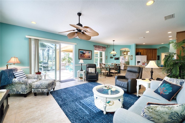 tiled living room with ceiling fan and a textured ceiling