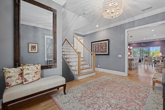 entryway with light wood-type flooring, crown molding, and a notable chandelier