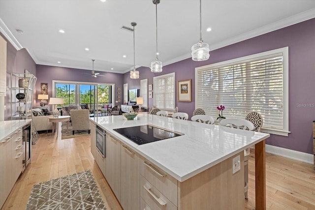 kitchen with hanging light fixtures, ceiling fan, black electric cooktop, a kitchen island, and a kitchen bar