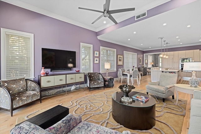 living room with light wood-type flooring, ceiling fan, and crown molding