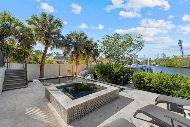 view of pool featuring a patio area, a water view, and an in ground hot tub