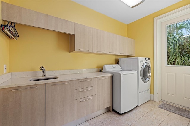 clothes washing area featuring cabinets, light tile patterned flooring, washer and clothes dryer, and sink